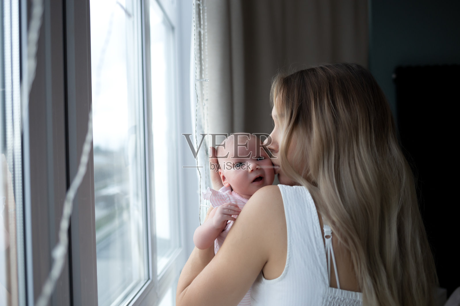 年轻美丽的女人亲吻她可爱的女儿。全家福照片摄影图片