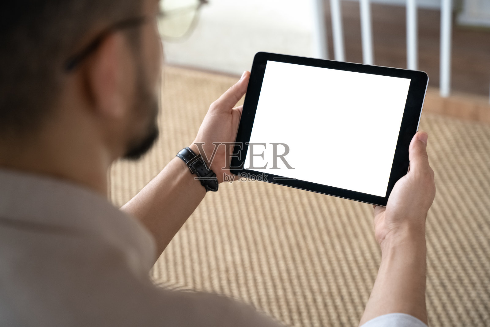 特写的印度人拿着数码平板电脑坐在沙发上的家庭办公室照片摄影图片