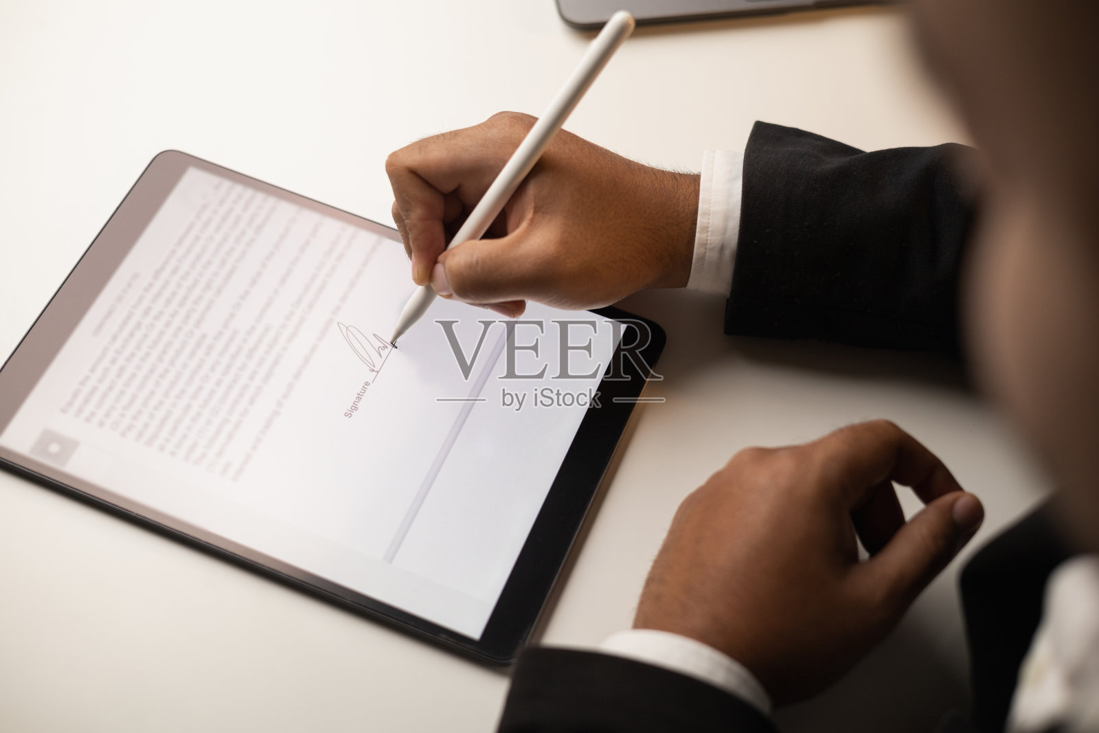 关闭商人手电子签名的平板电脑手写笔。撰写商务合同协议书。男子在平板电脑上签合同。商业和技术概念。照片摄影图片