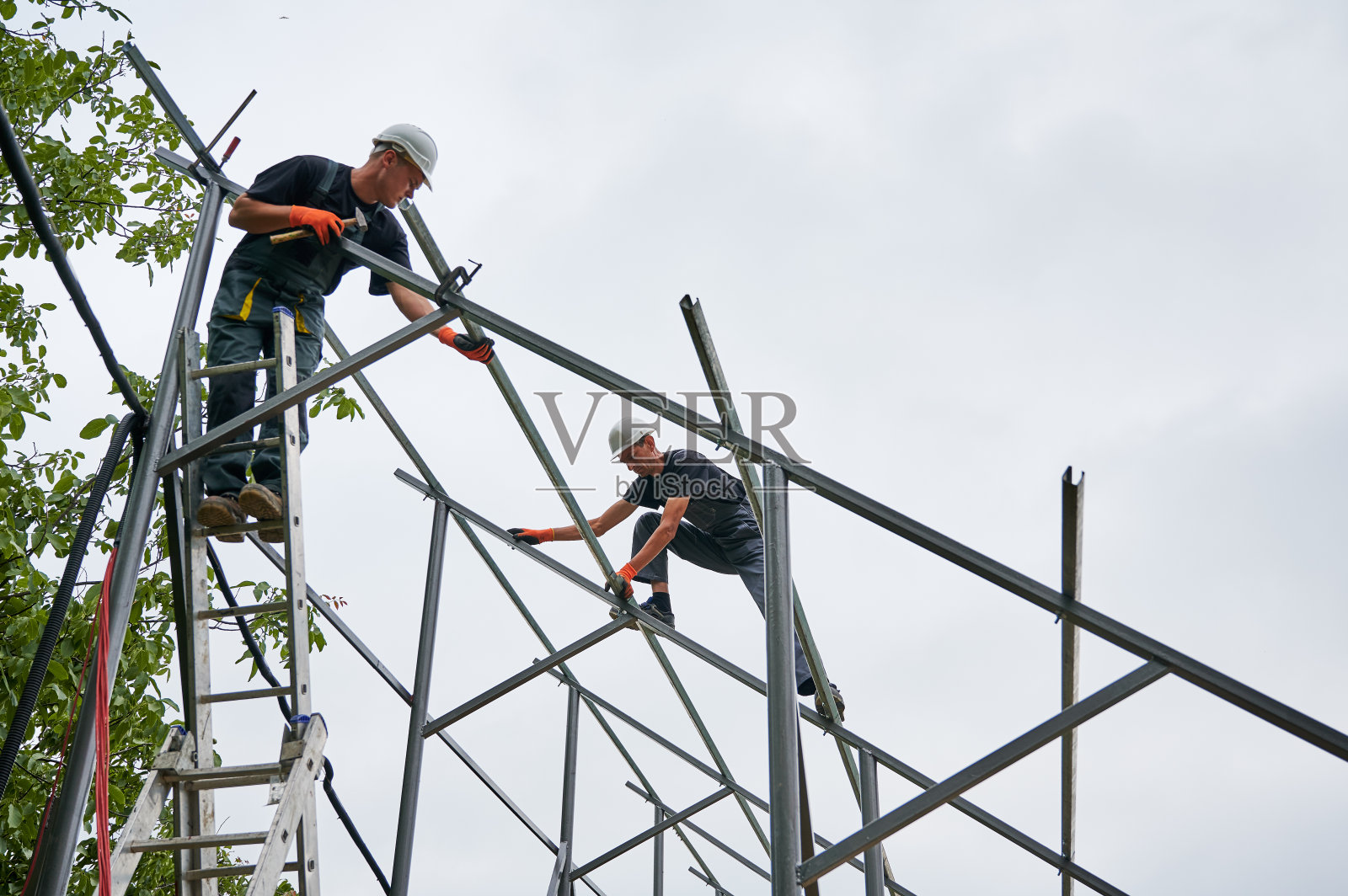 为太阳能电池板安装金属杆和栏杆的男性工人。照片摄影图片