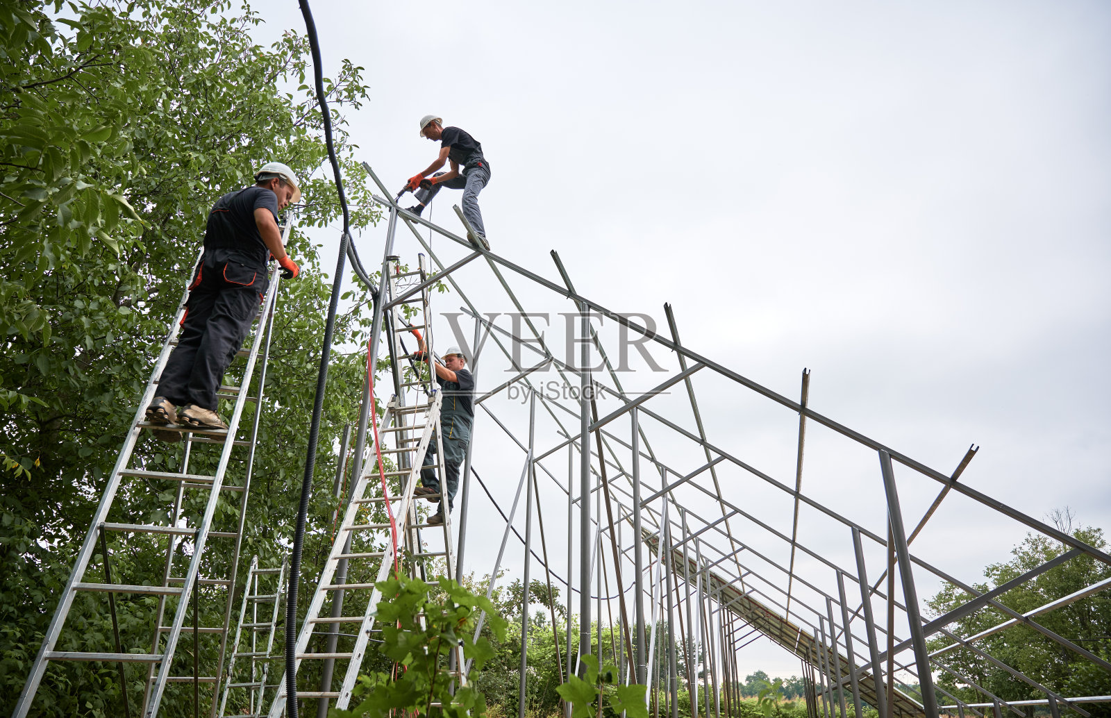 男工人在白色的天空下安装太阳能电池板系统。照片摄影图片