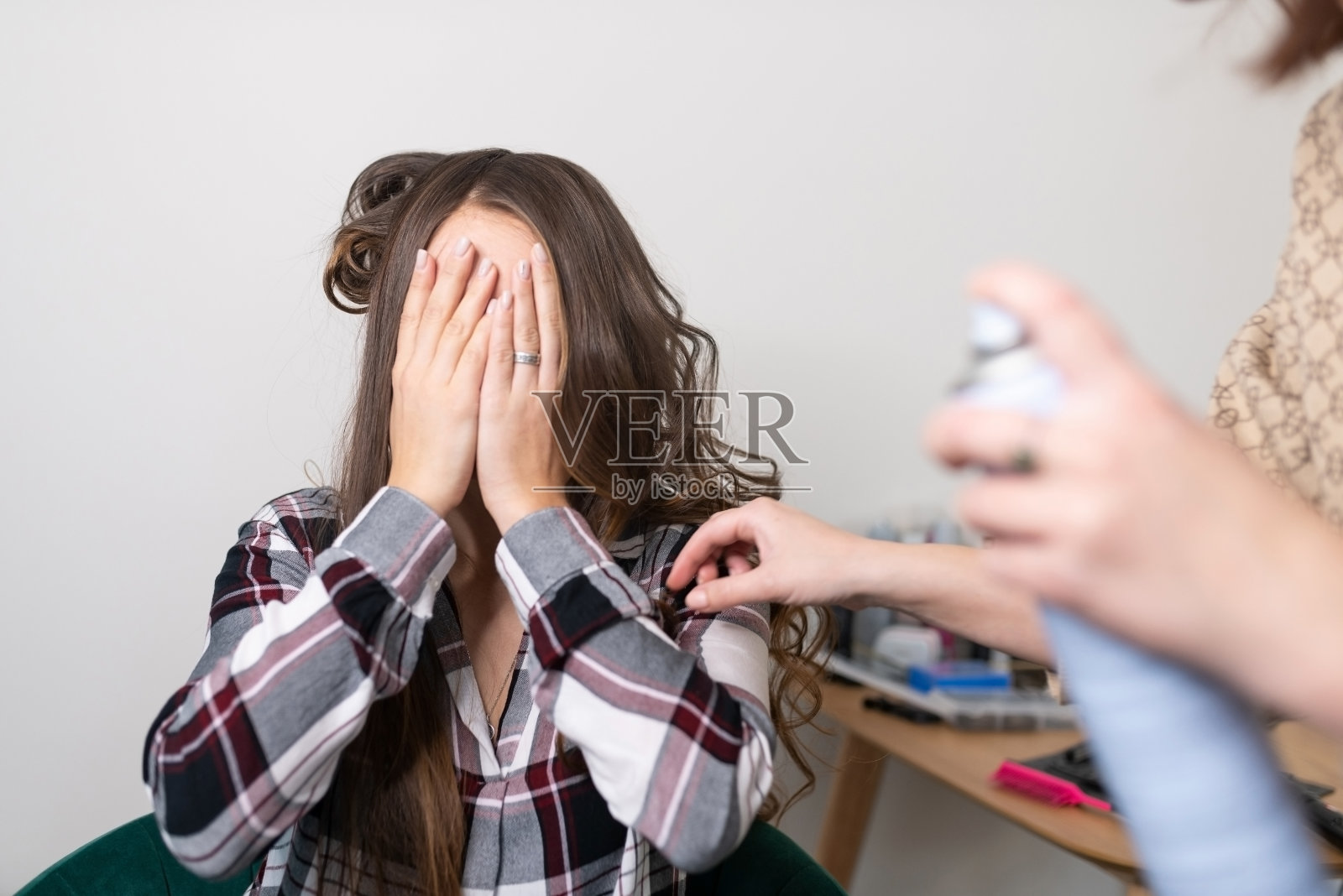 发型师给女孩上发胶时，女孩用手捂住了脸照片摄影图片