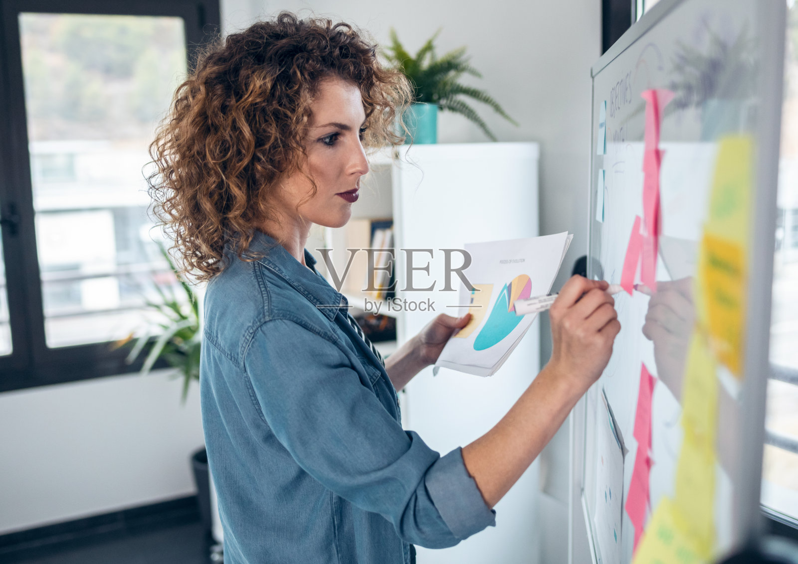 漂亮的女商人一边工作一边在办公室白板上写头脑风暴。照片摄影图片