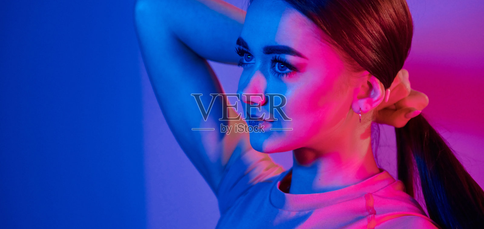 侧视图。时尚的年轻女子站在工作室霓虹灯照片摄影图片