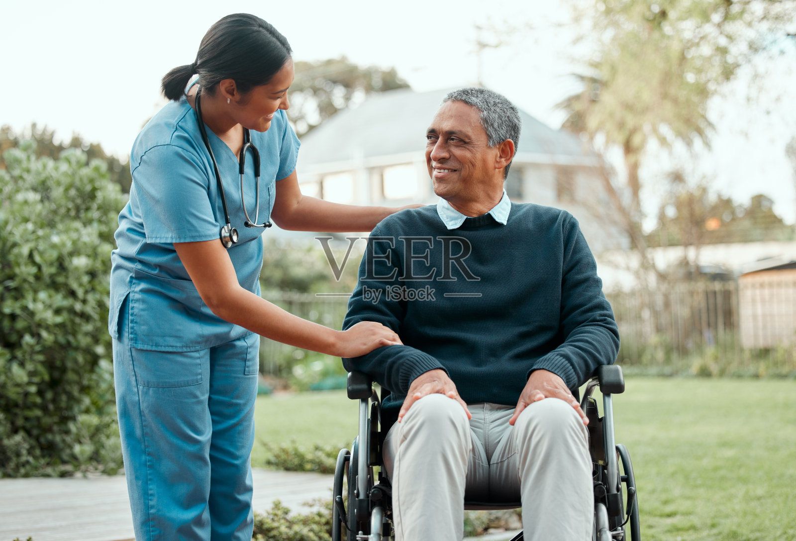 拍摄的是一个年轻的护士照顾一个坐在轮椅上的老人照片摄影图片