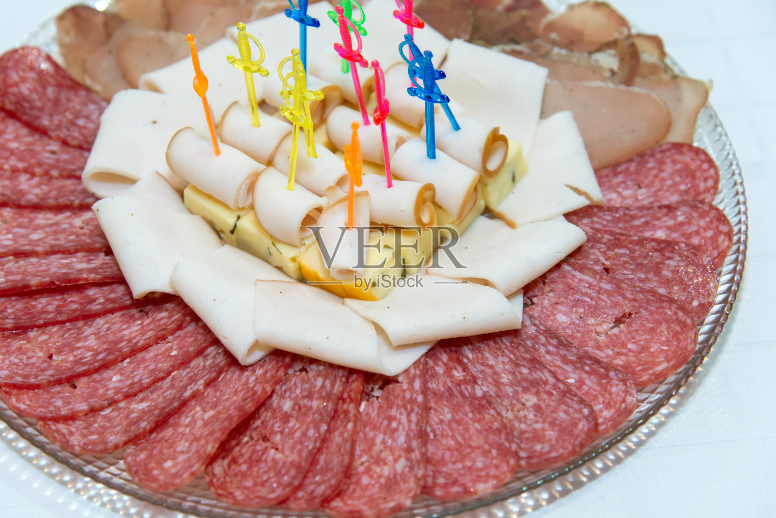 活动的配餐食物-不同类型的美味肉类和奶酪，安排在一个盘子上，背景很亮-招待会上的自助餐。宴会服务。方的概念。照片摄影图片