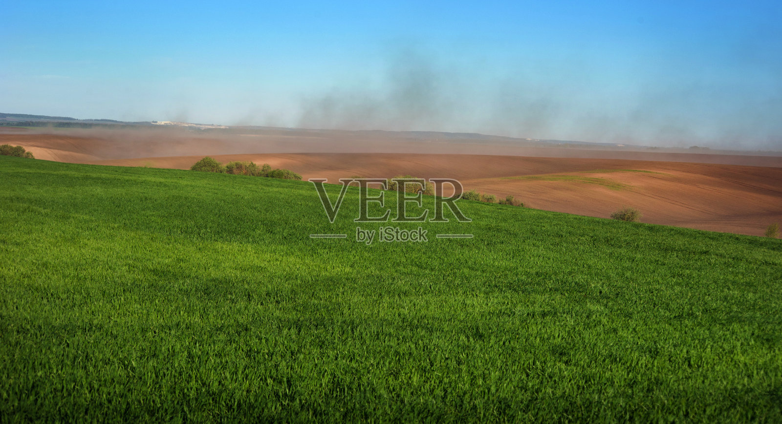 绿油油的田野里，冬小麦和云雾笼罩着丘陵的耕地，土壤受到风的侵蚀照片摄影图片