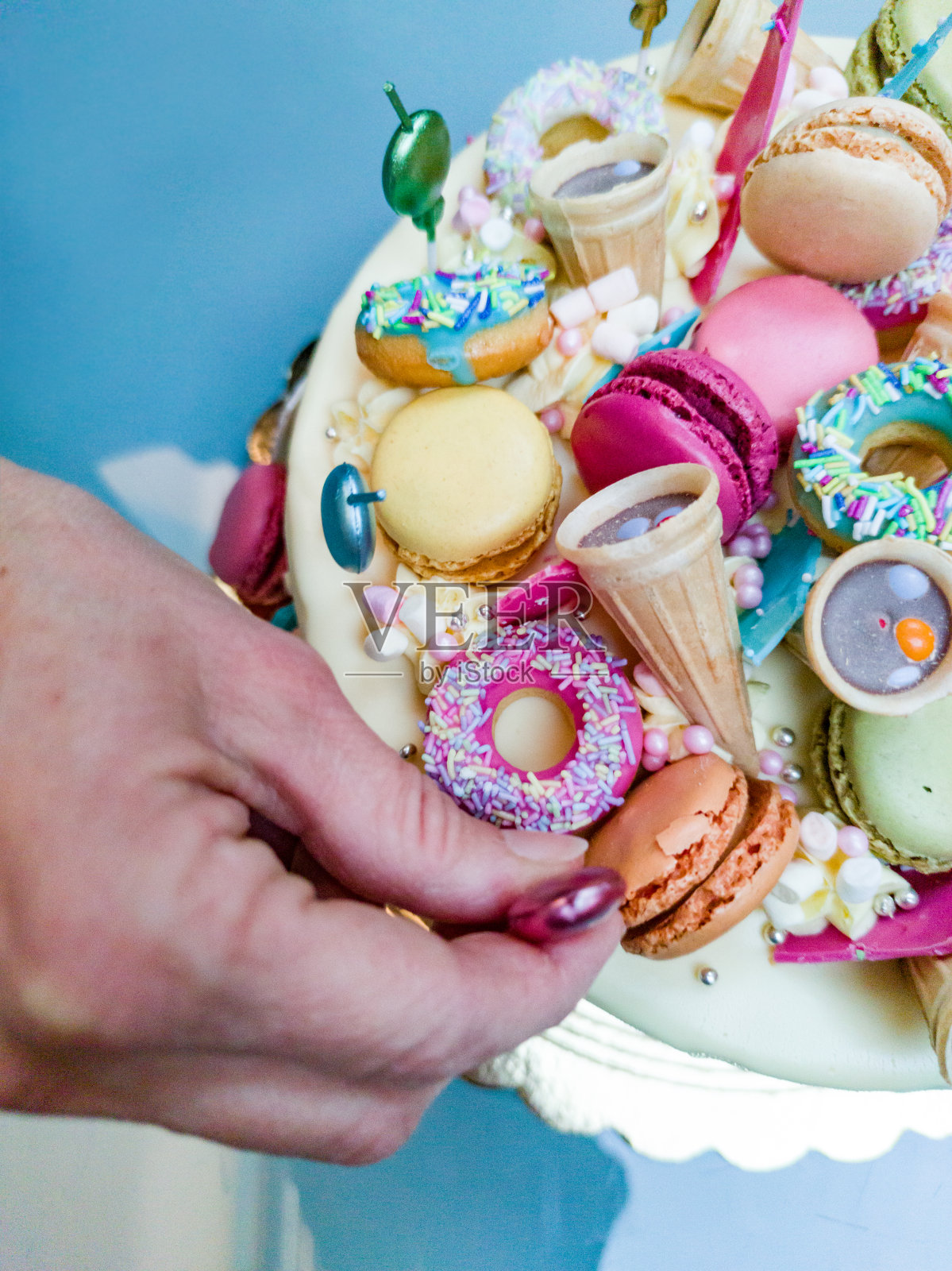 女人的手用蜡烛装饰彩色的生日蛋糕照片摄影图片