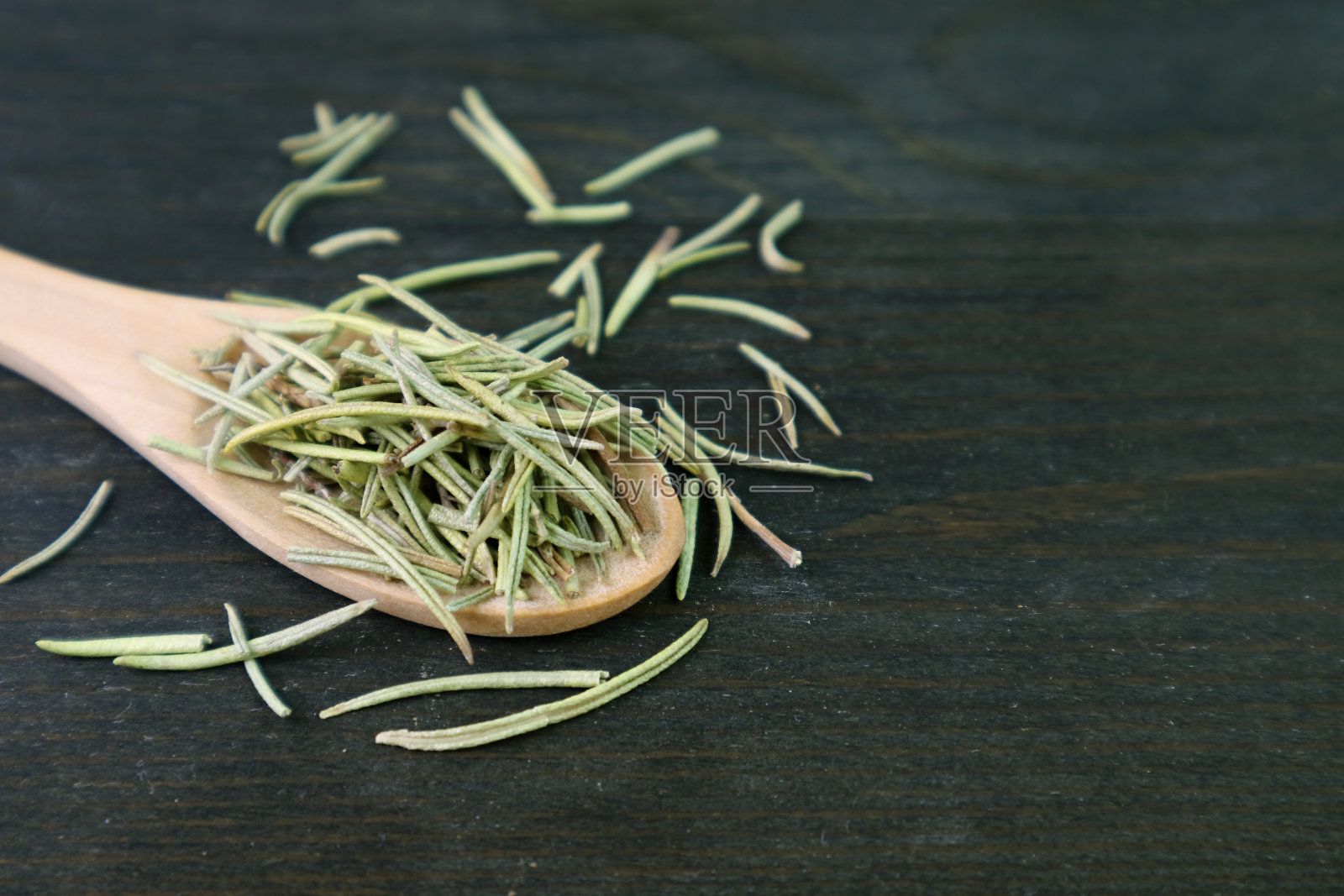 在黑色木制背景上，勺子里的芳香的干迷迭香的特写照片摄影图片