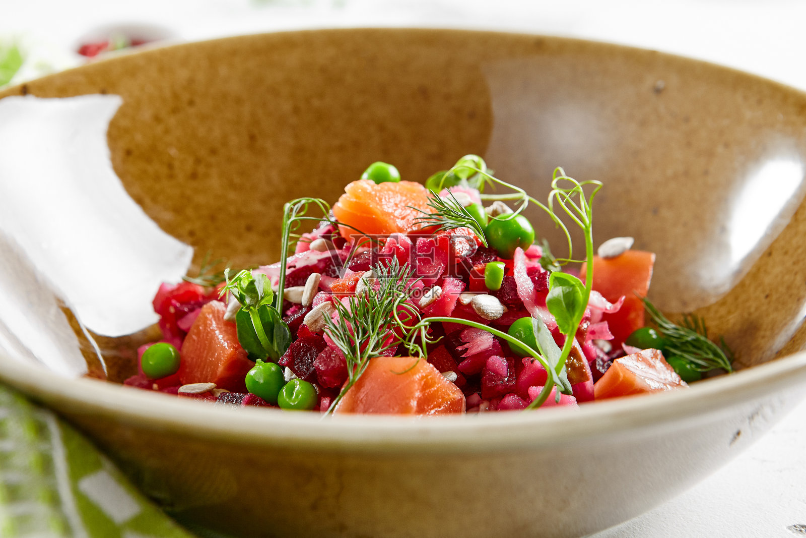 传统的俄罗斯沙拉——用煮熟的蔬菜、卷心菜和青豆制成的油醋汁。乡村风格的鲑鱼香醋沙拉。素食菜在碗石背景。俄罗斯的食物。照片摄影图片