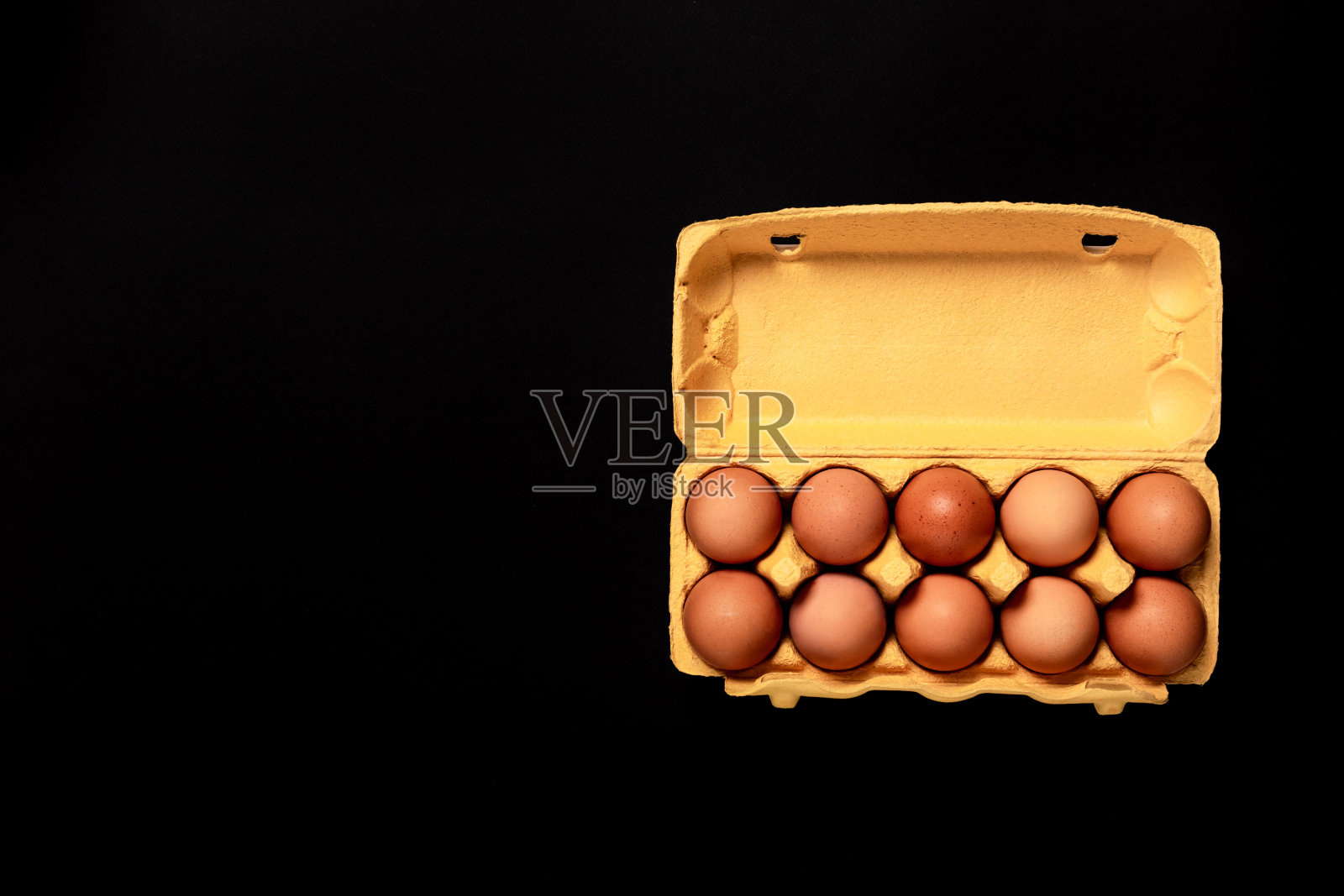 天然有机鸡蛋在黄色硬纸板包装孤立在黑色背景，俯视图，与拷贝空间，空文本的地方。杂货店的名片。农场新鲜的食物。健康饮食照片摄影图片