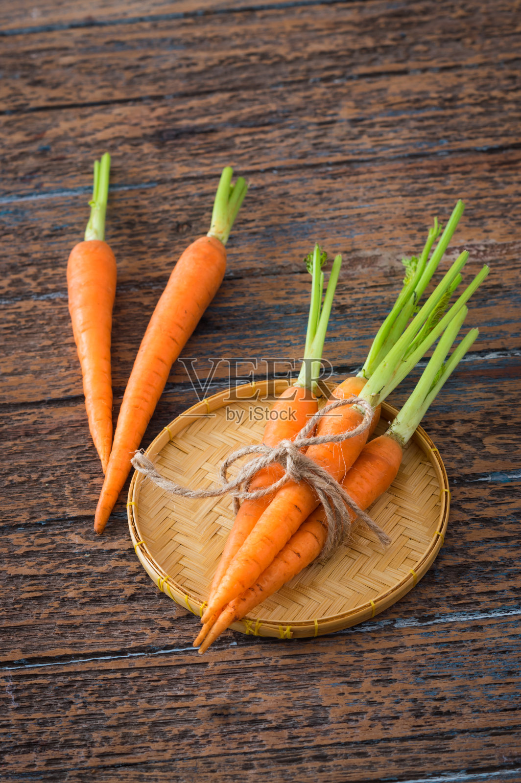 桌上放着新鲜的胡萝卜和小篮子。照片摄影图片