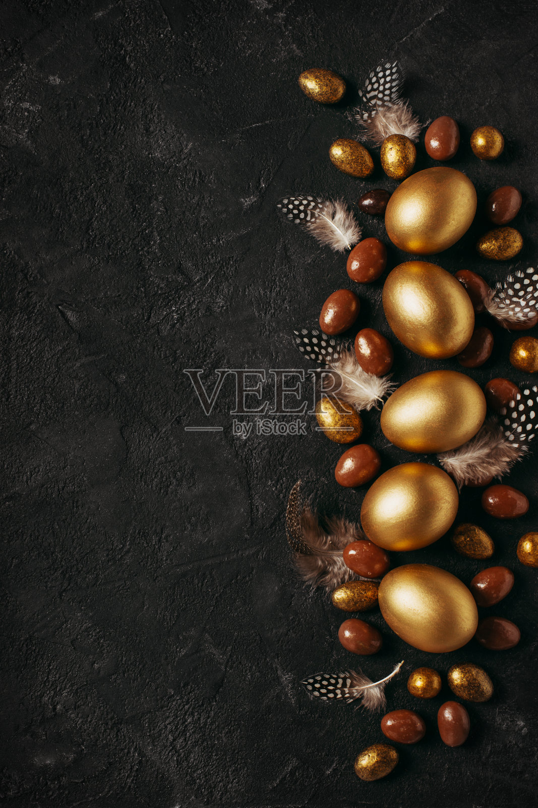 快乐的复活节概念平躺与金蛋和羽毛在黑色的背景照片摄影图片