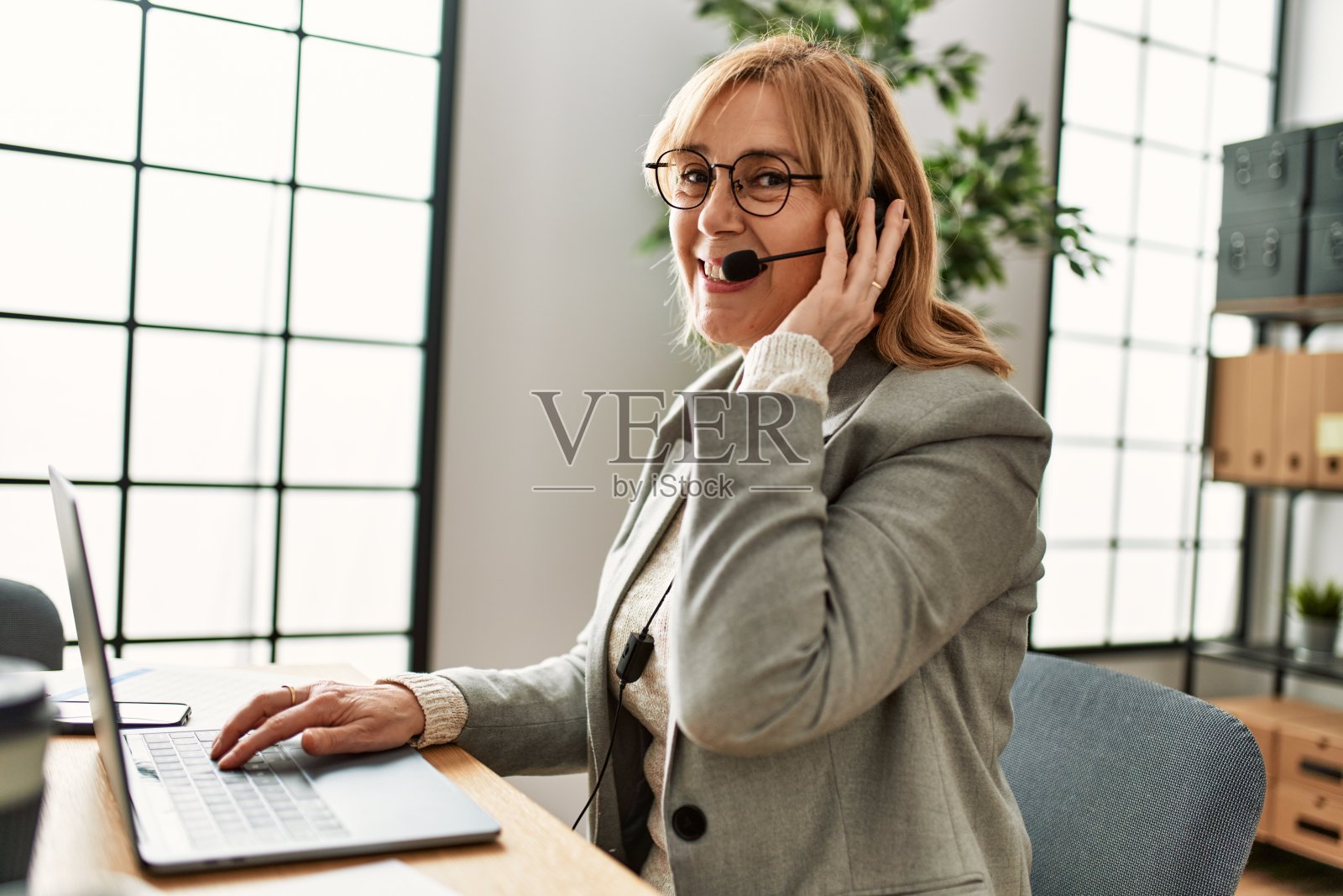 中年呼叫中心代理，在办公室工作。照片摄影图片