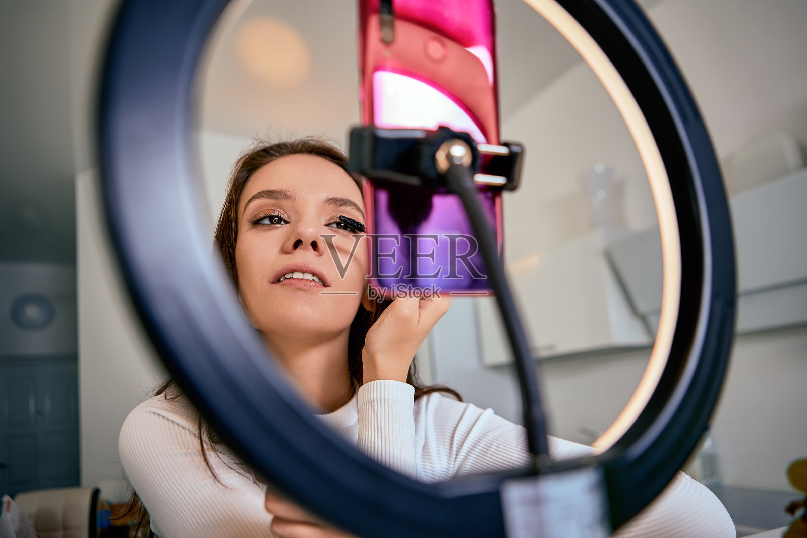 由女博主用戒指灯和手把手直播的化妆教学。照片摄影图片