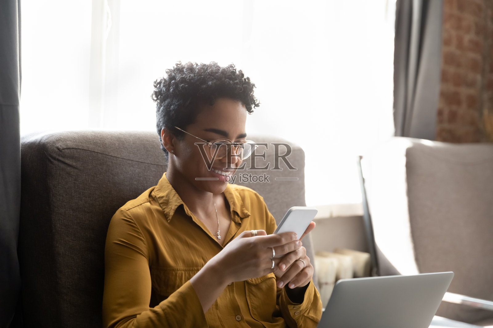 一名快乐的非洲裔年轻女性正在使用智能手机。照片摄影图片