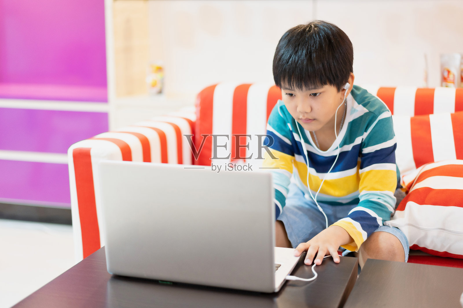 在居家隔离期间，亚洲男孩使用笔记本电脑进行在线学习。家庭教育、在线学习、家庭隔离、在线学习、冠状病毒或教育技术概念照片摄影图片