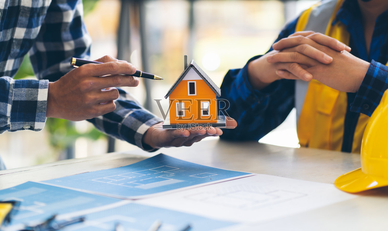 建筑师和工程师会议计划一个新项目，桌上放着施工设备，建筑师和工程师在图纸和房屋模型上工作。照片摄影图片