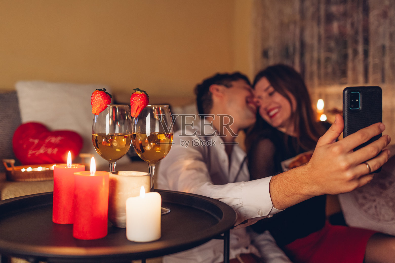 情人节，情侣们拿着酒杯在手机上自拍，在家里吃着浪漫的晚餐照片摄影图片