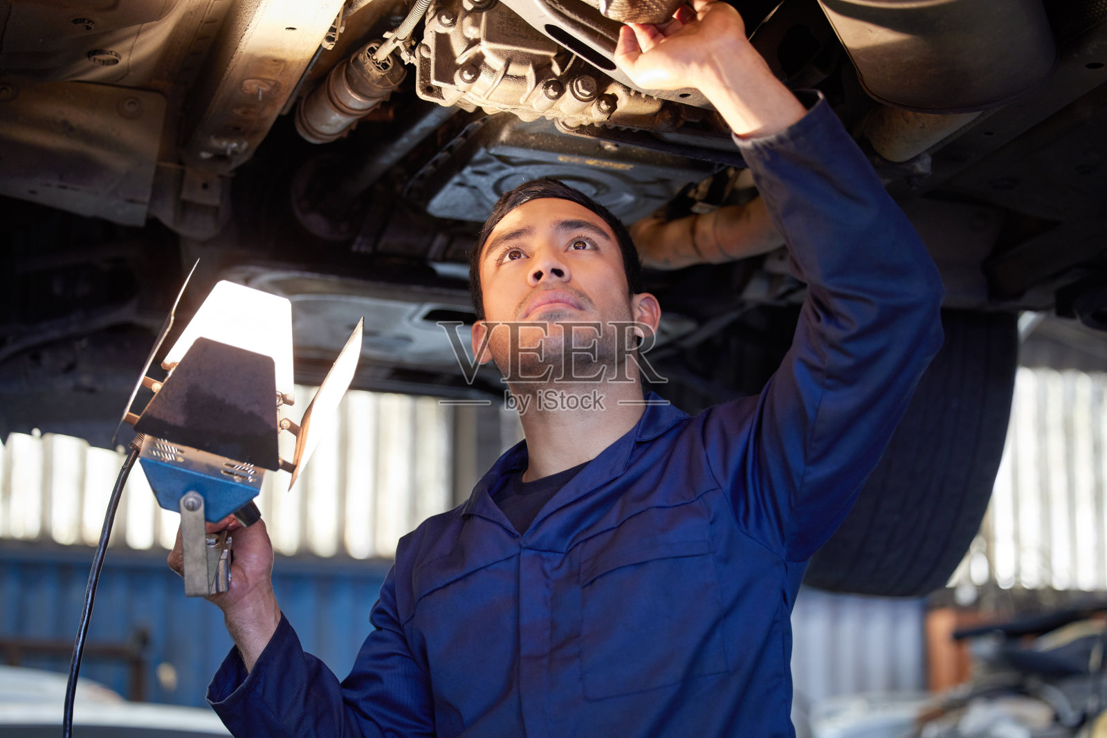 剪裁镜头的一个英俊的年轻男性机械师工作在一个服务期间的汽车引擎照片摄影图片