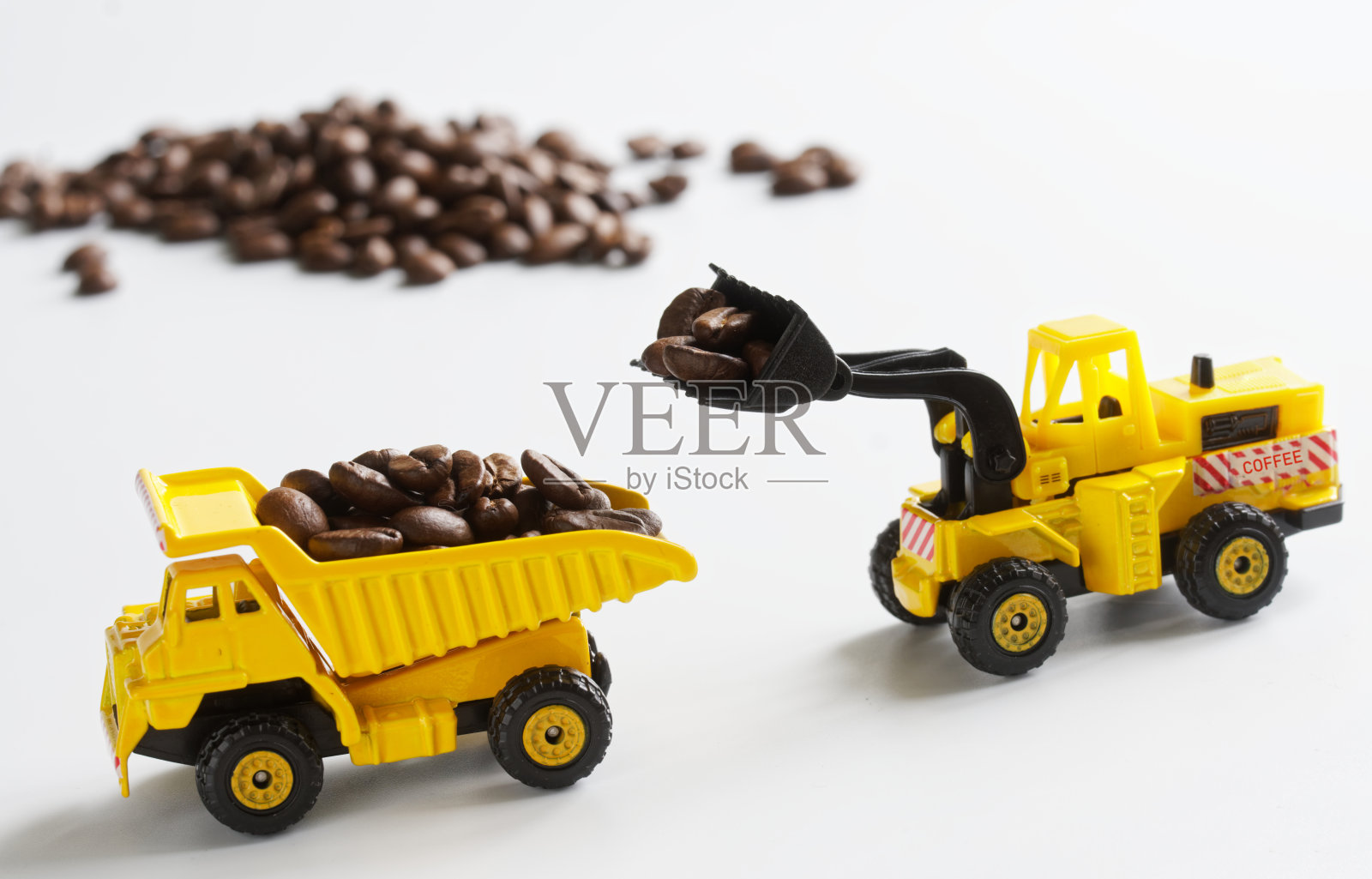玩具车把咖啡豆装进一辆自卸卡车的后部。白色背景。农业工作的概念，收获和运输作物照片摄影图片