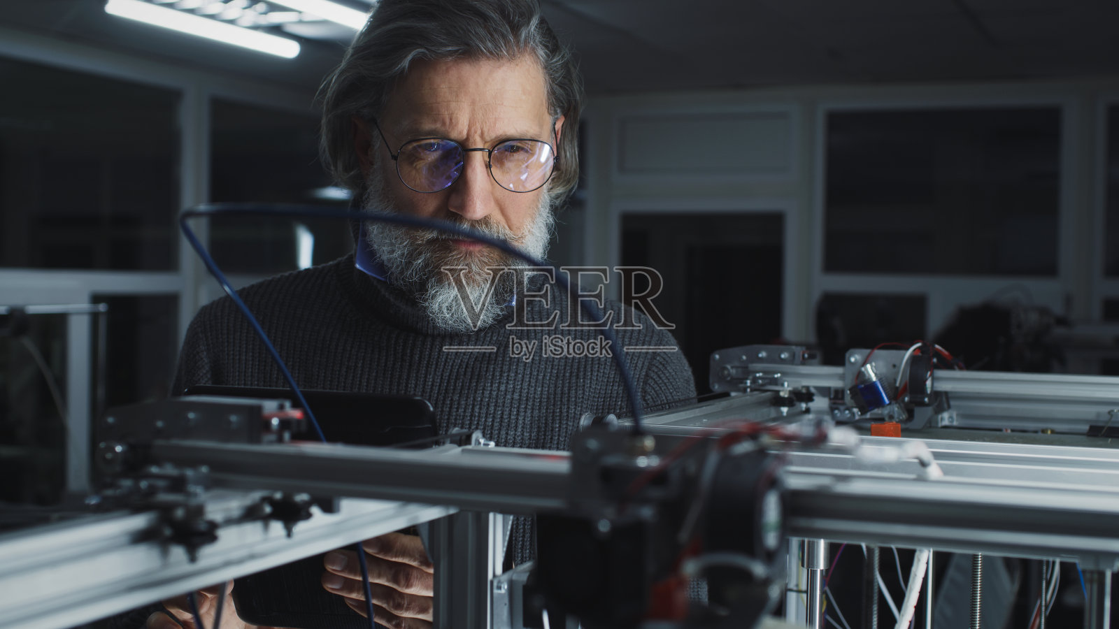 成熟的设计师观看3D打印机的工作照片摄影图片