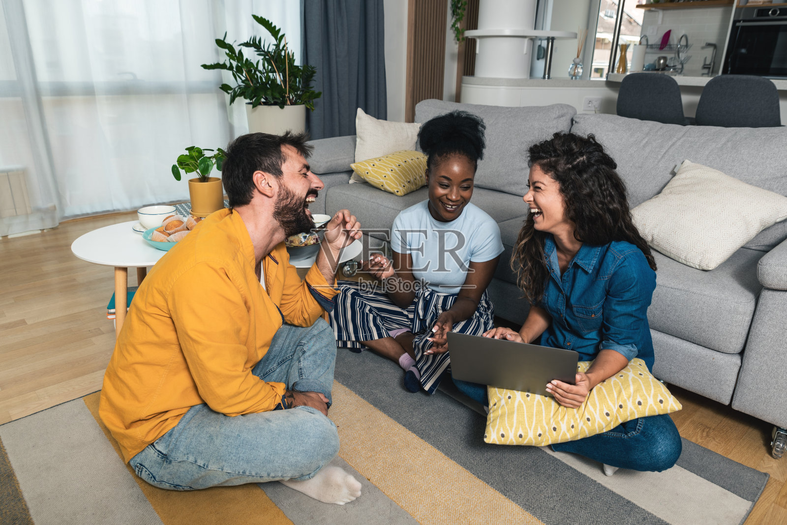 一群年轻的创意成功的朋友坐在他们的现代家庭办公公寓的地板上休息，从自由职业者的工作。自由职业者男人和女人在一起照片摄影图片