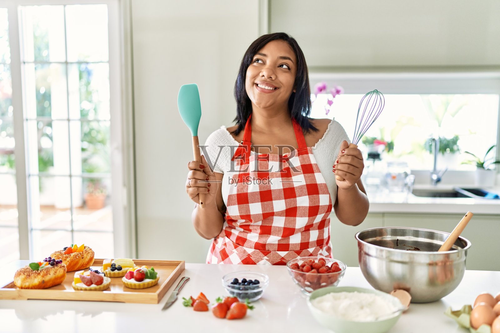西班牙黑发妇女准备糕点与水果在厨房的搅拌器照片摄影图片