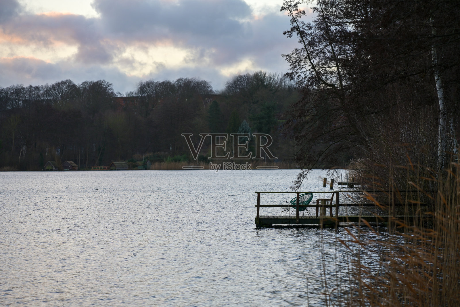 木制船坞与椅子作为剪影，在灰黑色的天气，田园诗般的风景在一个不舒服的季节，复制空间照片摄影图片