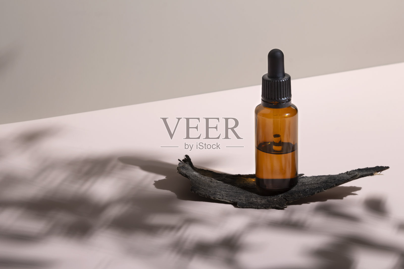 皮肤护理彗星似的。滴瓶精油与硬植物阴影和树树皮讲台上柔和的中性粉红色背景。照片摄影图片