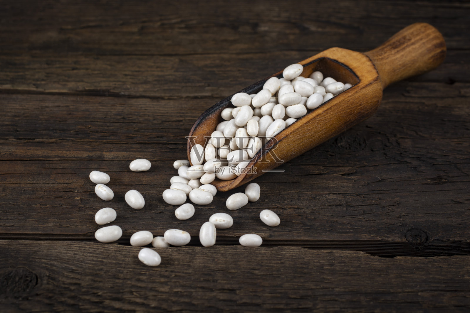 木勺里的生豆子放在桌子上。照片摄影图片