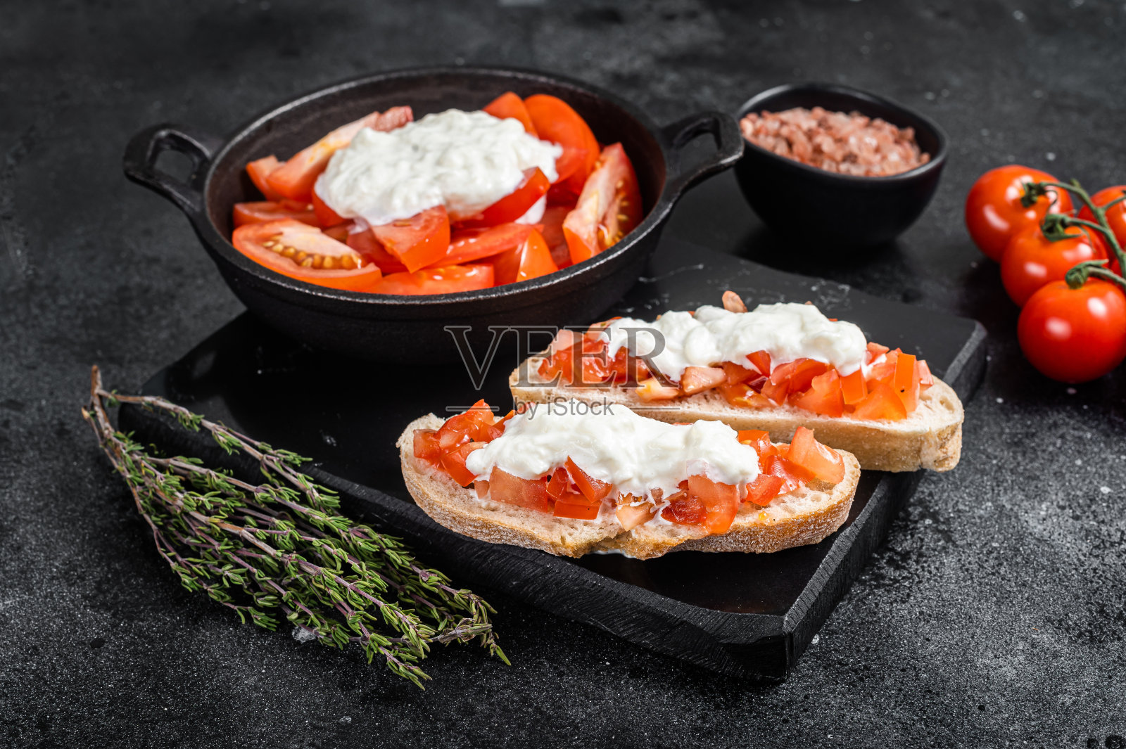 脆脆的意式烤面包，配意大利干酪，番茄末和百里香。黑色背景。俯视图照片摄影图片