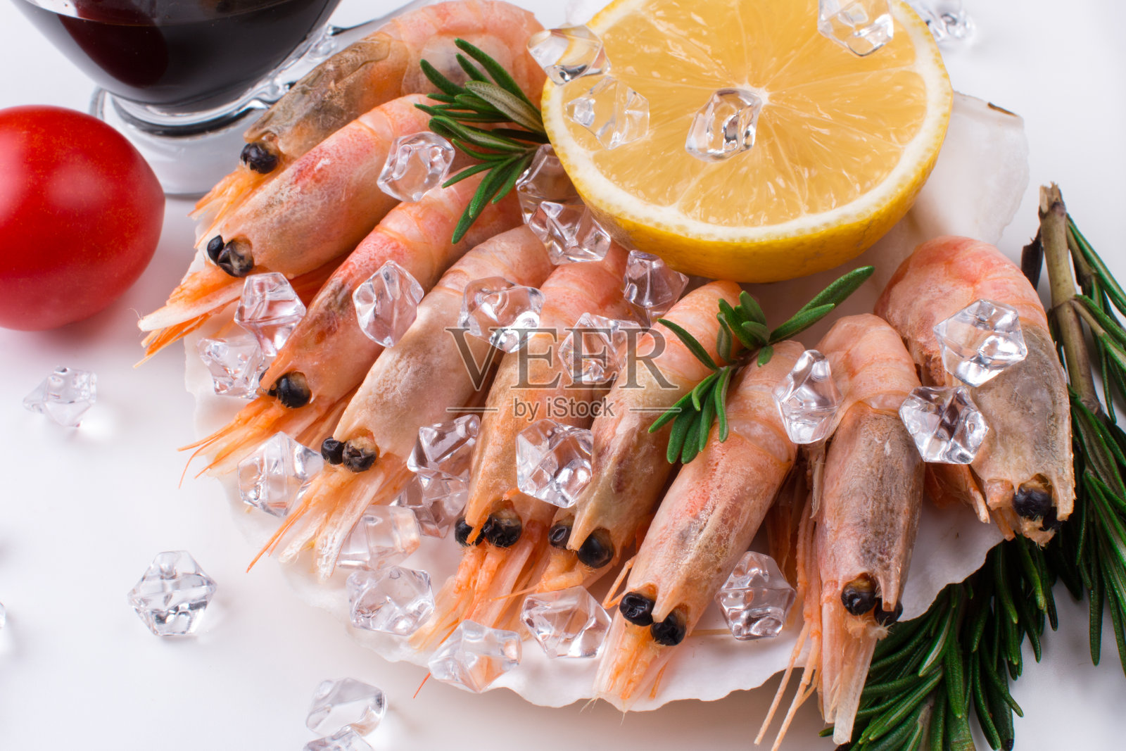 生虾被冰包裹在贝壳里。餐厅供应及销售海鲜。白色底色的柠檬酱虾照片摄影图片