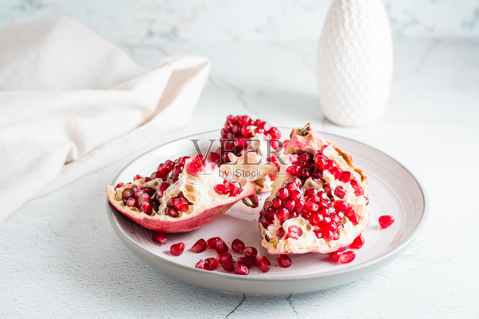 一个完整的成熟的石榴被分成几块放在一个盘子上，放在一张轻便的桌子上。有机天然食品。生活方式照片摄影图片