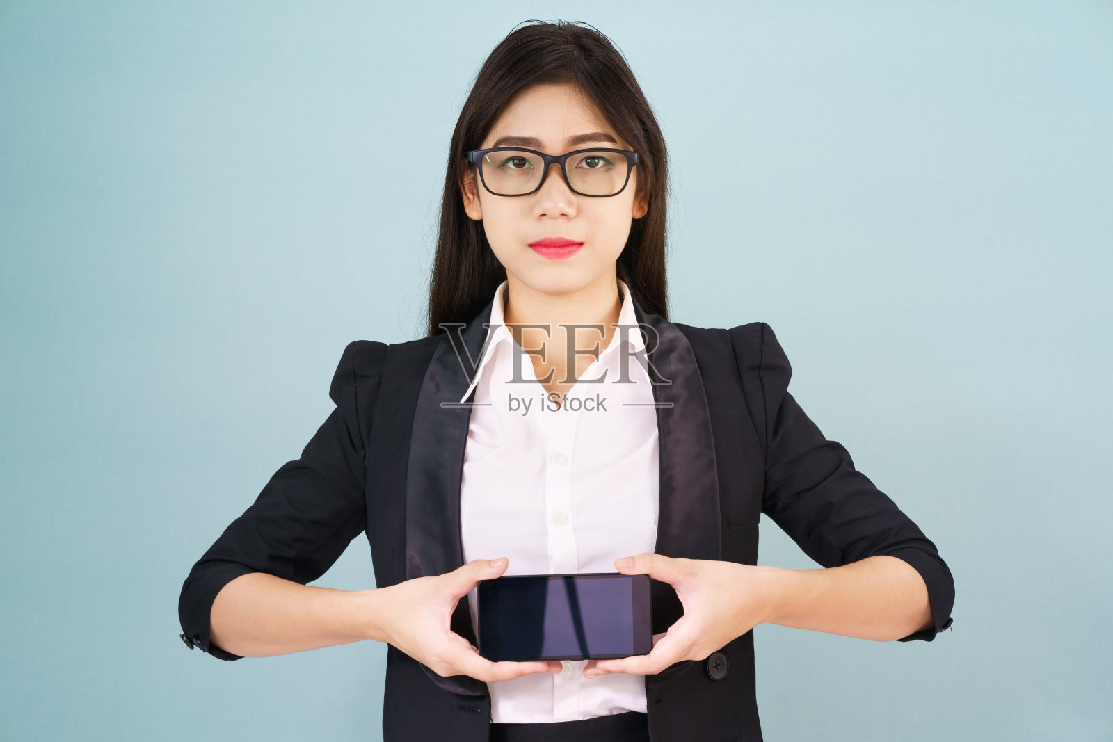 穿着西装拿着智能手机的年轻女性照片摄影图片