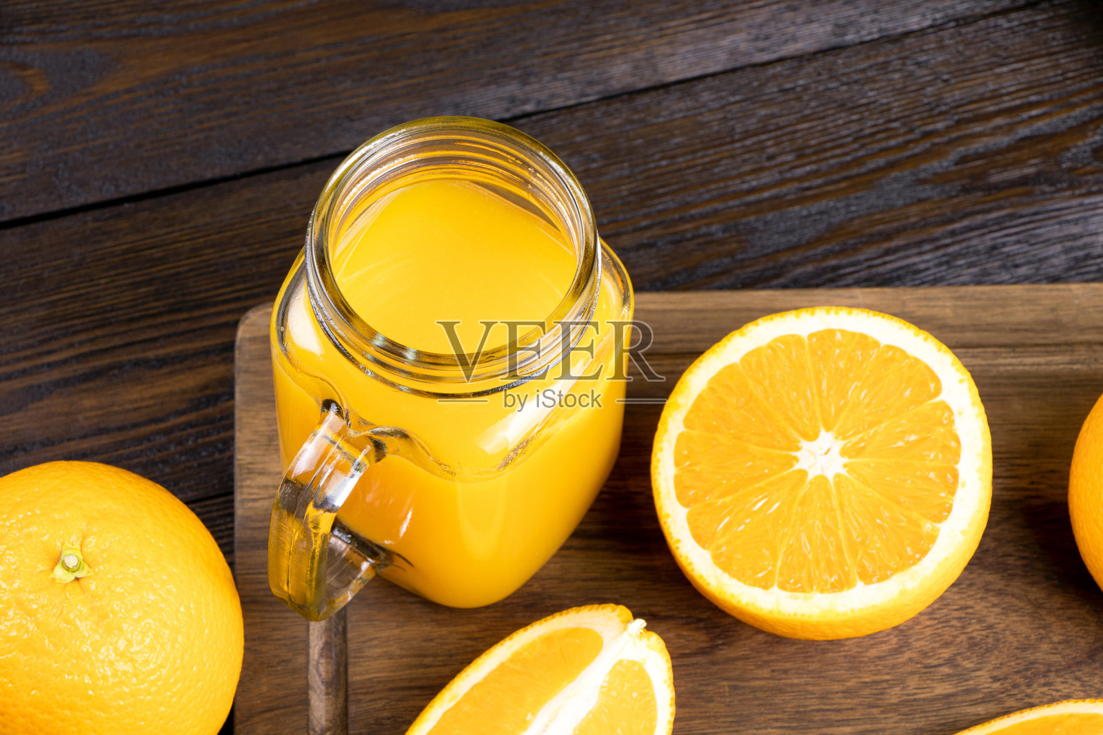 鲜橙汁装在玻璃杯里，木质背景。新鲜的橙色水果，带有绿叶。健康的素食。维生素的食物。成熟的橘子。平的。垂直方向。照片摄影图片