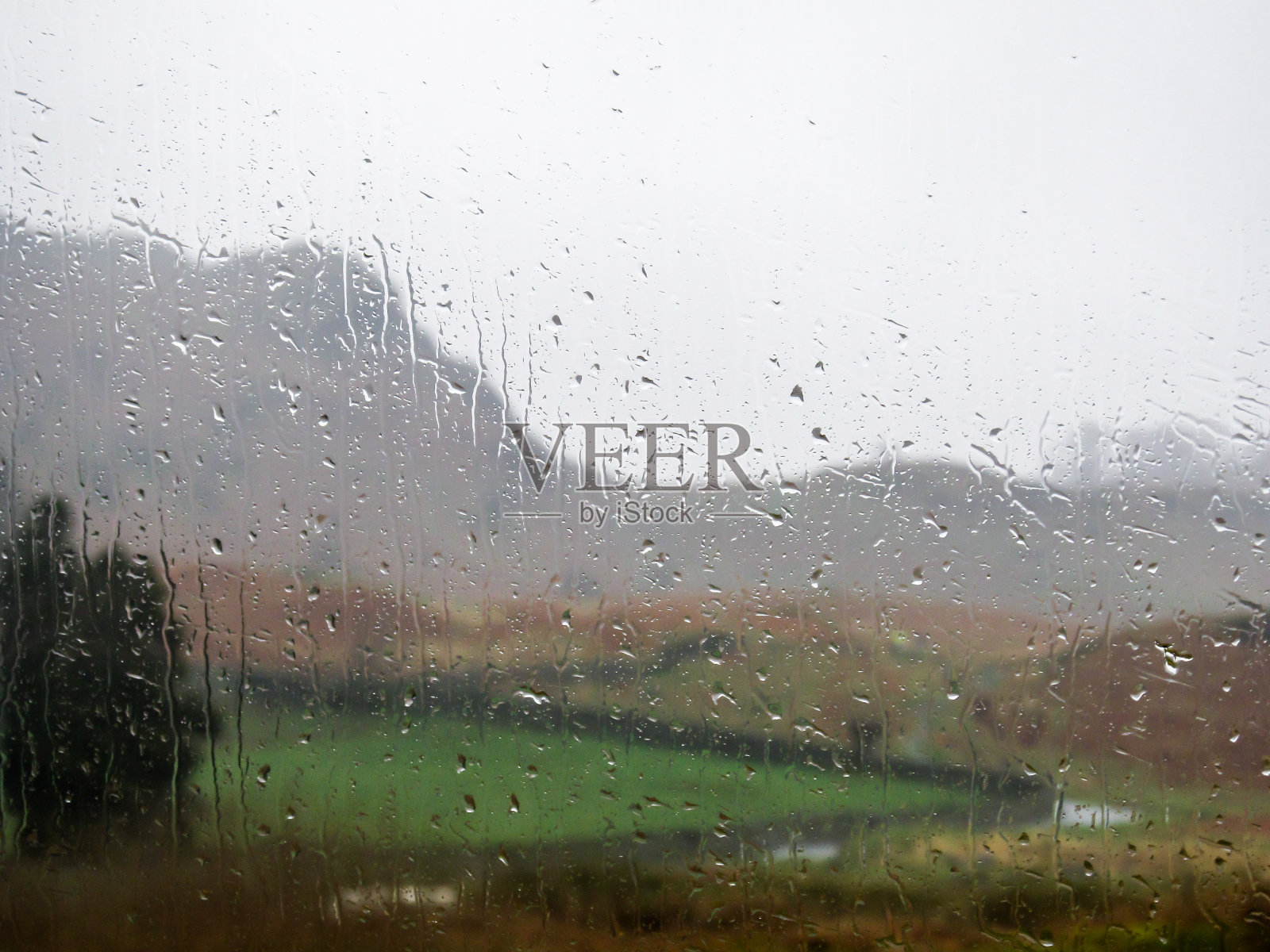雨点落在窗户上，背景是湖区的模糊风景照片摄影图片