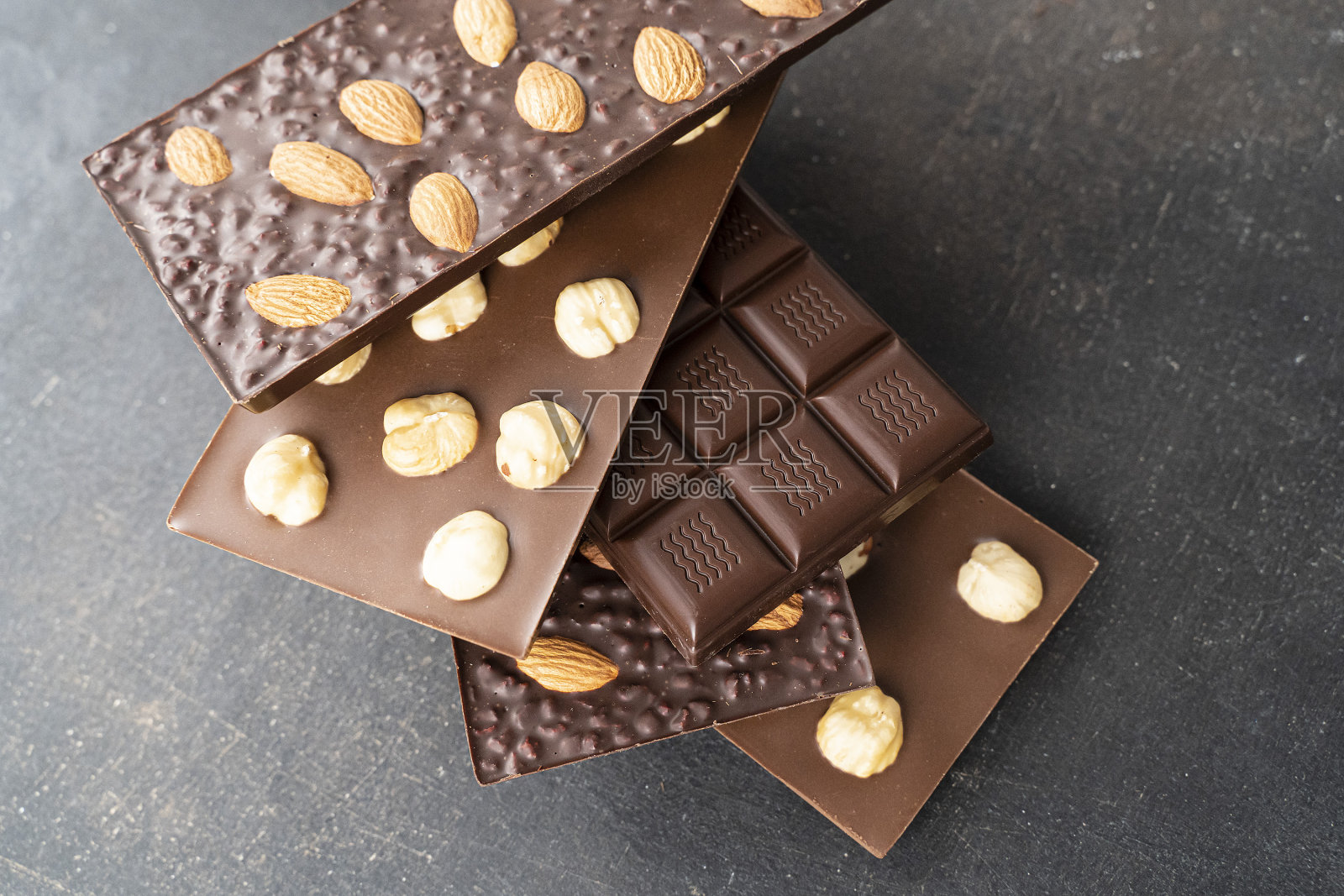 杏仁巧克力棒，榛子巧克力棒，手工糖果。在黑色的背景上，牛奶和黑杏仁巧克力榛子的组成条，俯视图。桌上的糕点工艺以巧克力为背景照片摄影图片