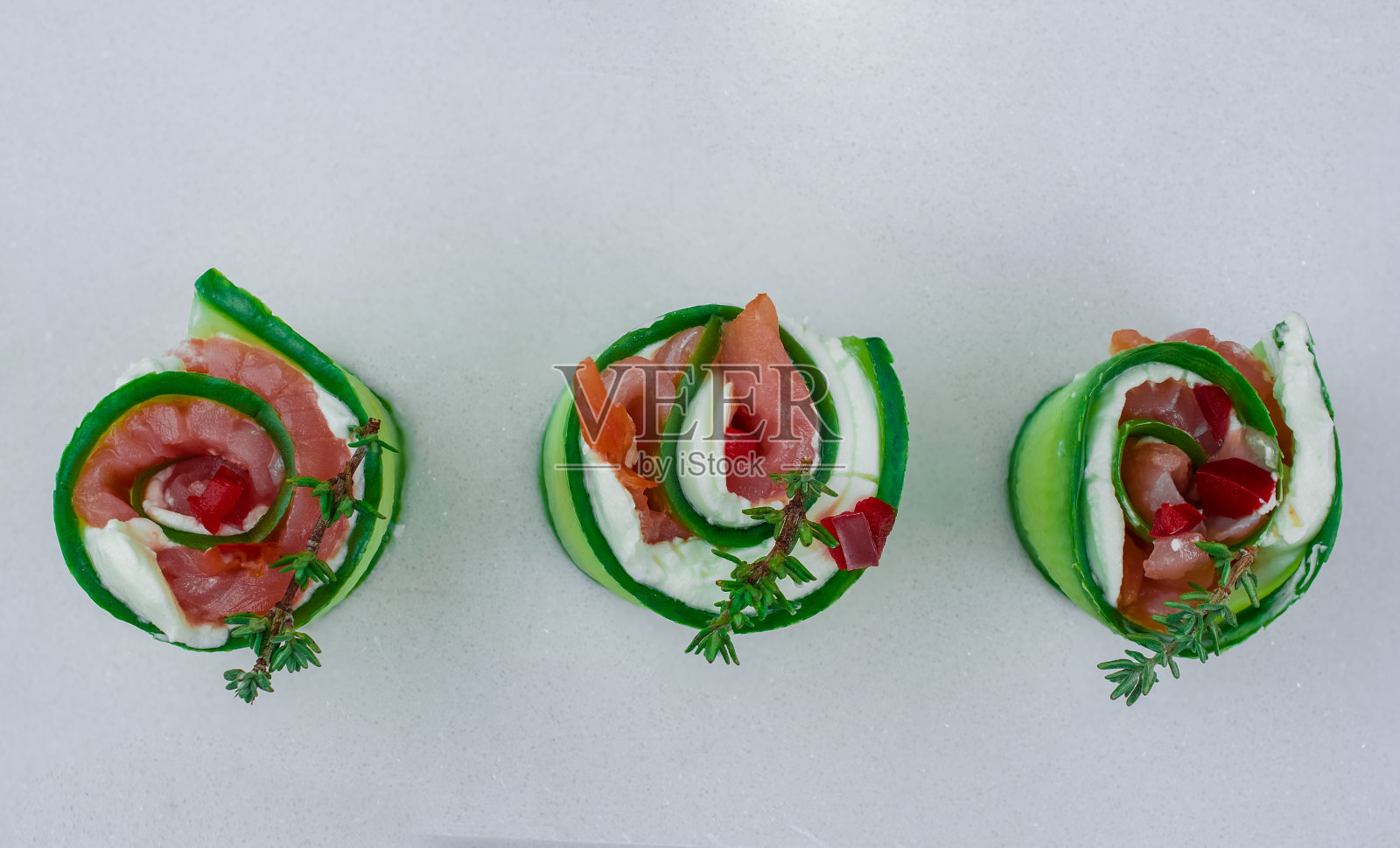 烟熏三文鱼配黄瓜和软奶酪卷放在白色盘子上照片摄影图片