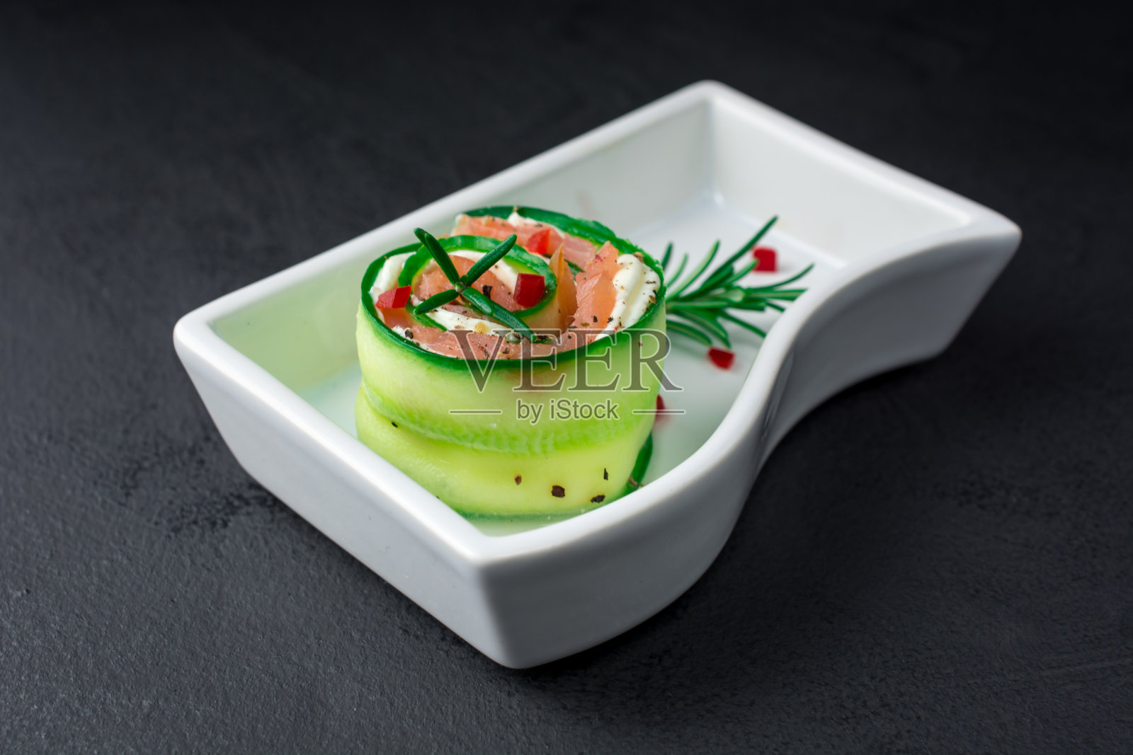 烟熏三文鱼配黄瓜和软奶酪卷放在白色盘子上照片摄影图片