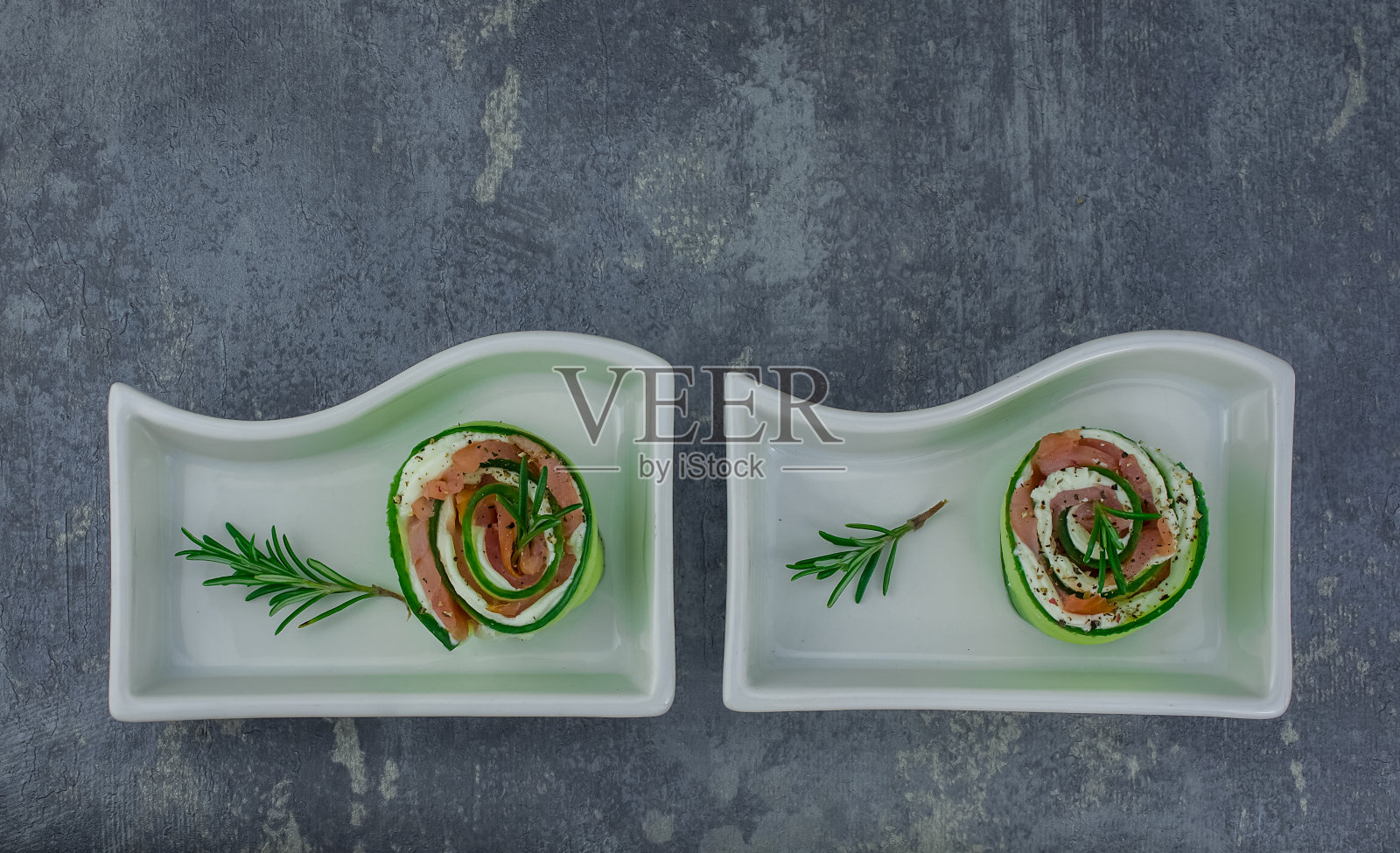 烟熏三文鱼配黄瓜和软奶酪卷放在白色盘子上照片摄影图片