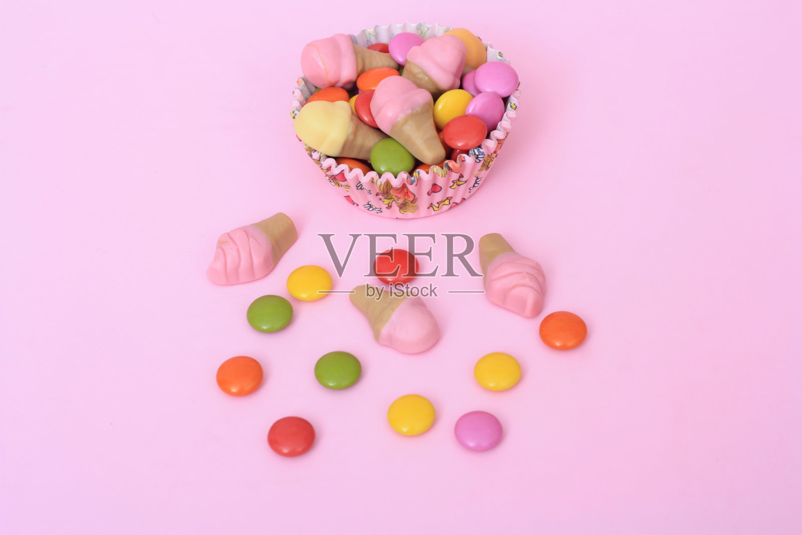 明亮的多色巧克力宝石在粉红色的背景照片摄影图片