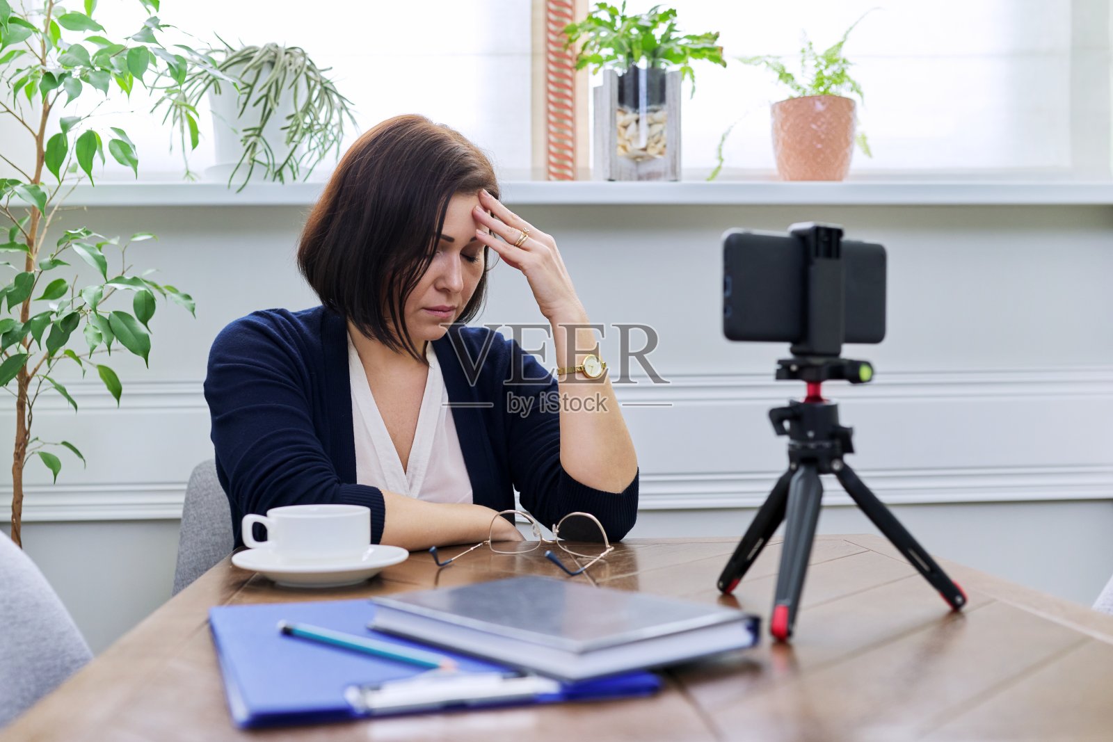 可悲的成熟商业女性在家里用智能手机开视频会议。照片摄影图片