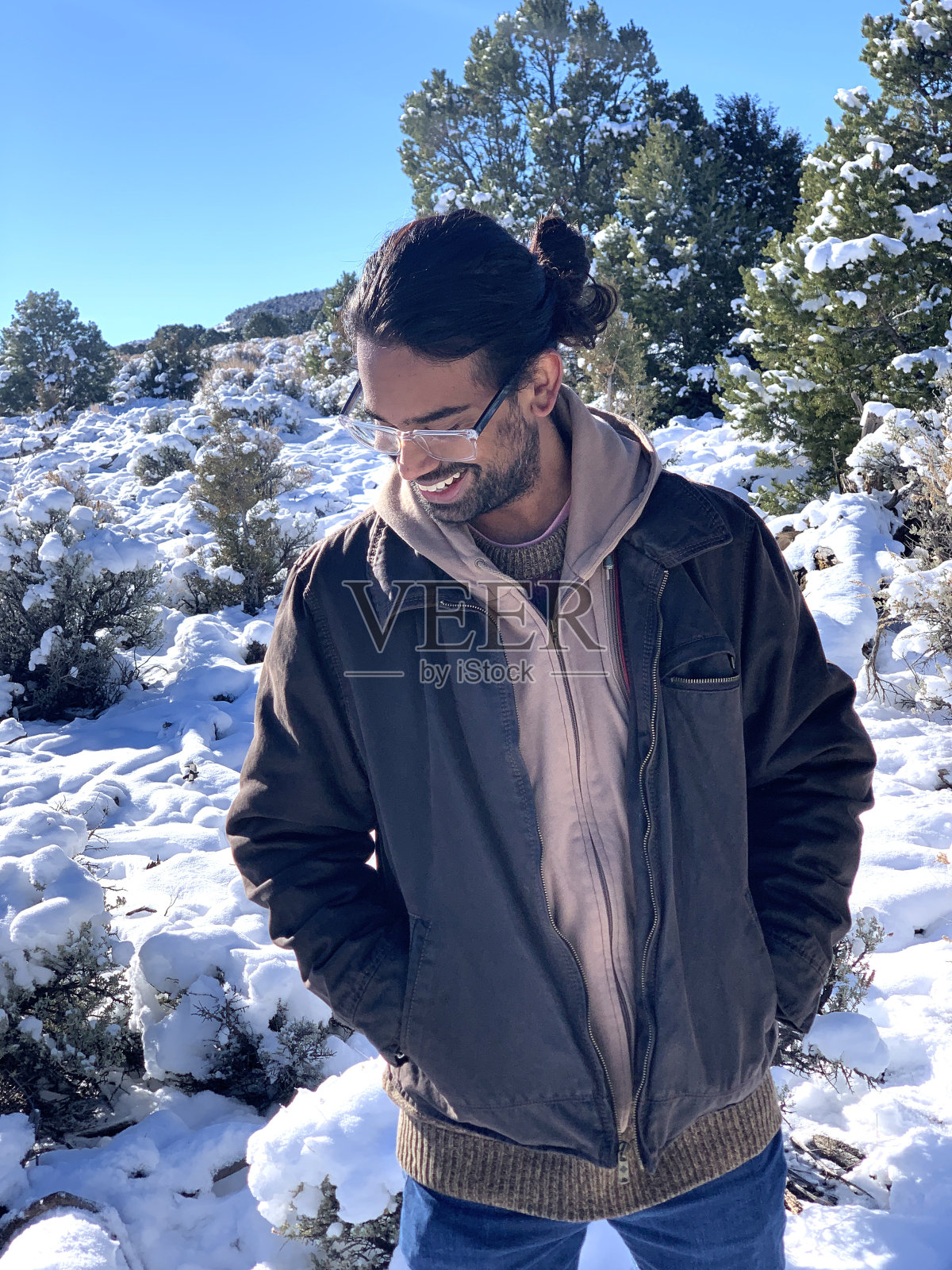 一个快乐的，时尚的亚洲印度青年男子站在一个阳光明媚的日子微笑在科罗拉多州的雪原高国家的肖像照片摄影图片