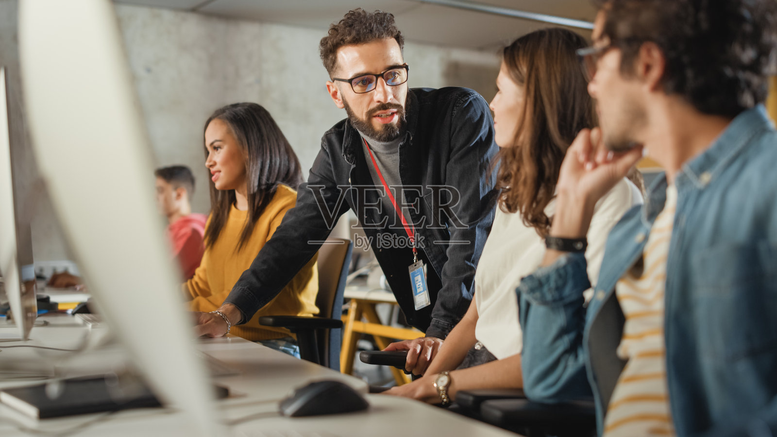 讲师帮助学者进行项目，对他们的工作提出建议。教师在大学里给不同种族的男女学生上课，教授计算机科学和编写代码。照片摄影图片