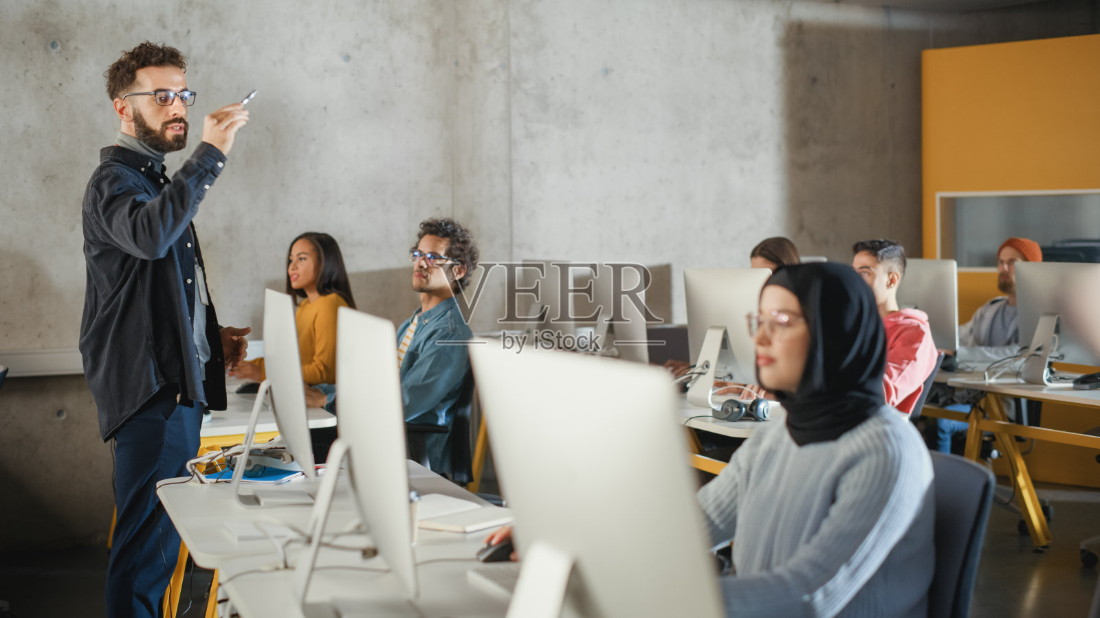 教师在大学房间里给不同种族的男女学生上课，在计算机上教授新的学术技能。讲师与聪明的青年学者分享知识。照片摄影图片