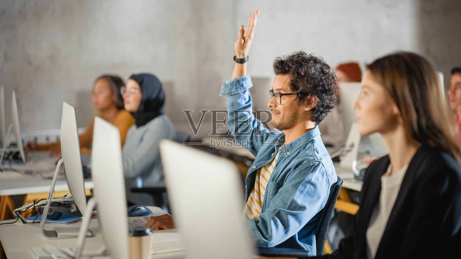 英俊聪明的男学生，在大学里与不同种族的同学一起学习。他举手问老师一个问题。在课堂上运用所学知识获取学术技能。照片摄影图片