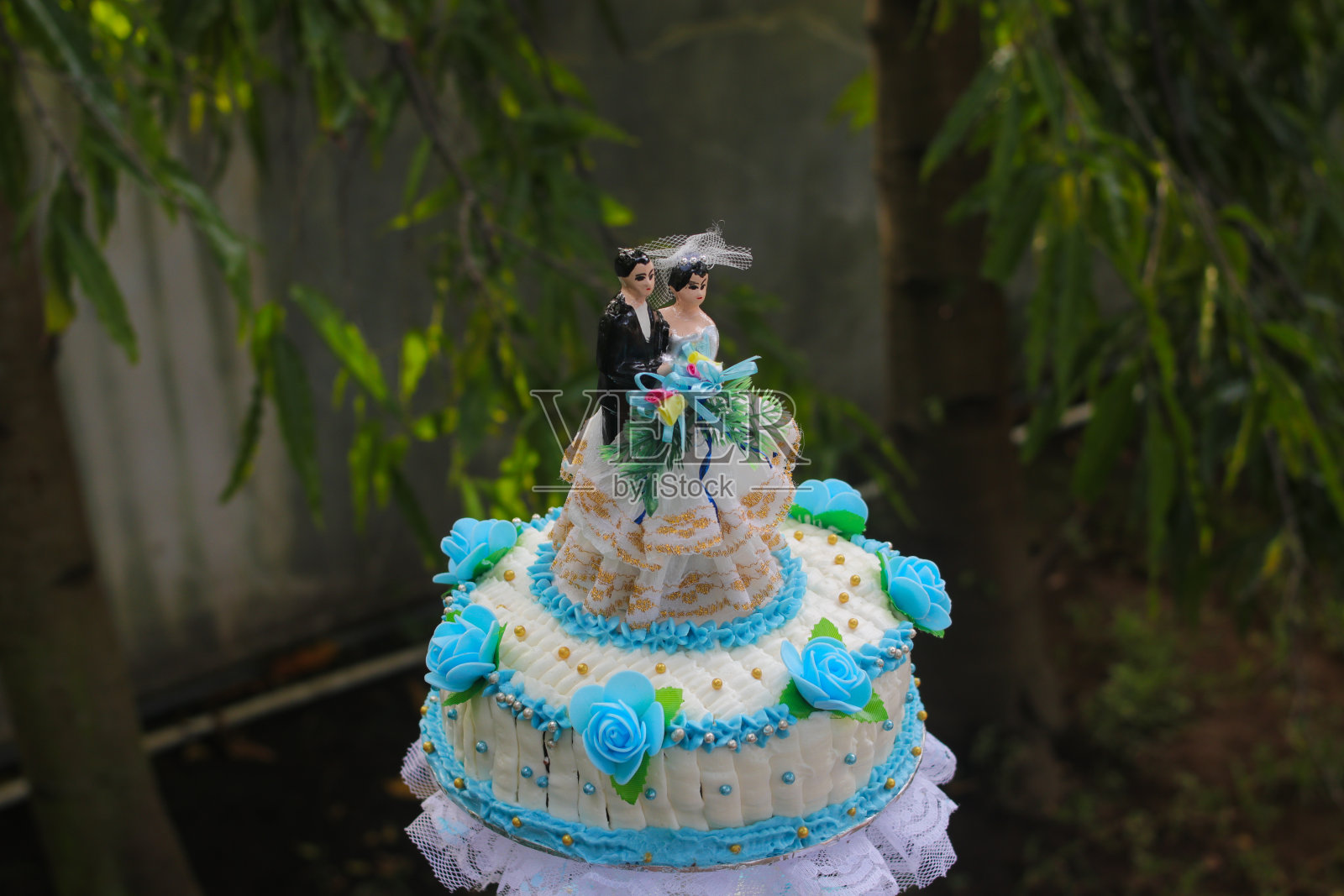 蓝色和白色的婚礼蛋糕与新人雕像和模糊的背景在户外婚礼的概念照片摄影图片