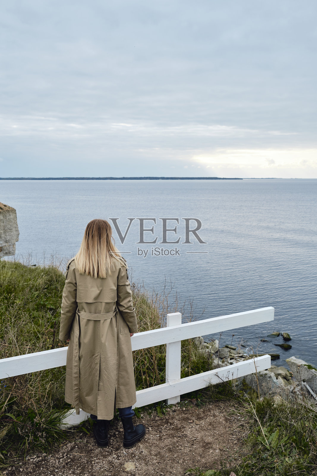 女孩站在悬崖边，看着大海。女人望向远方。令人惊叹的自然风景。美丽的岩石和大海。和谐、轻松的生活方式。旅行,冒险照片摄影图片