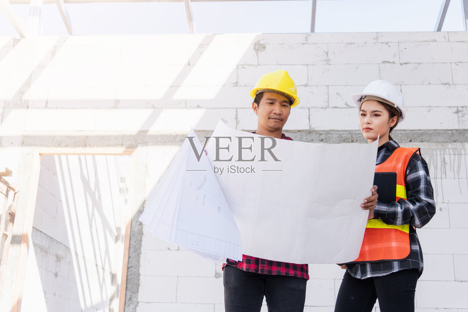 建筑师和业主在施工现场讨论建筑平面图照片摄影图片